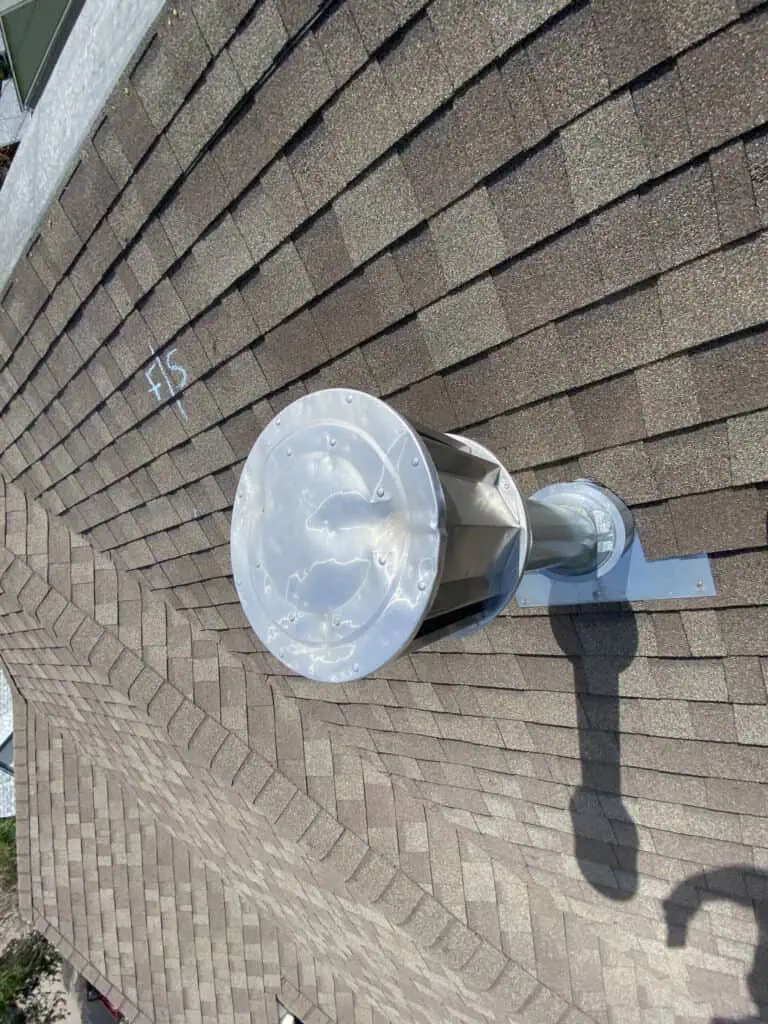 A metal roof vent is installed on a brown shingled roof. A shadow is cast beside it, and the number 515 is marked in white on the shingles nearby.